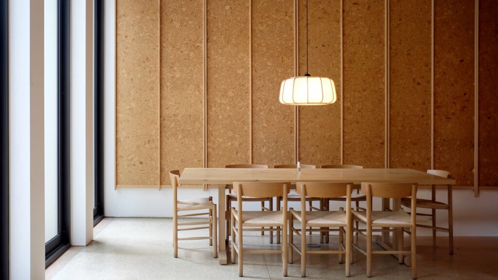 Salle avec mobilier en bois clair et revêtement mural en liège, créant une atmosphère chaleureuse.